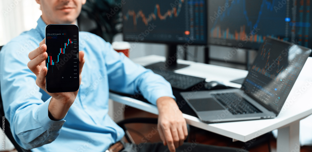 Poster successful young business trader showing dynamic stock market graph on smartphone, presenting infoma