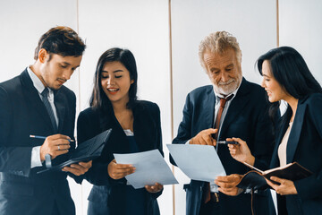 Senior caucasian manager working in office with assistance of young Asian business people and...