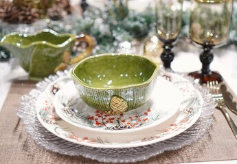 festive table setting for New Year's dinner in winter with the help of porcelain plates with a linen napkin and a salad bowl with glass glasses and with forks and a knife on the table with