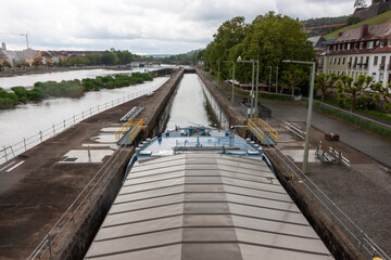 A large barge passes under the bridge, entering the lock channel