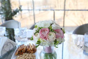 Wedding floral arrangement on a table in a restaurant photographed in ambiental light.