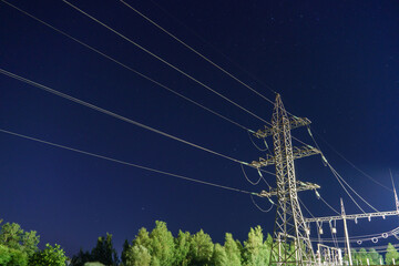 Power lines and high-voltage wires against the background of the night sky. Energy infrastructure...