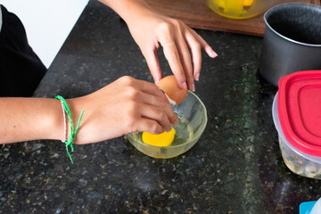 Young Woman Preparing a Homemade Recipe by Cracking a Fresh Egg into a Bowl