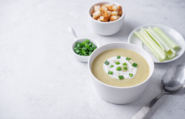 Celery greens soup with scallions and croutons in a bowl