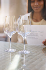 Glasses, woman and menu in restaurant for wine tasting, date or brunch in winery. Fine dining, order and female person with drink list in cafe, stem glass and table in vineyard for luxury or alcohol