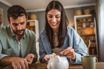 Happy boyfriend and girlfriend save money together in the piggy bank
