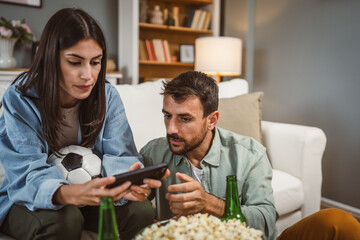 couple watch football match together on mobile phone at home