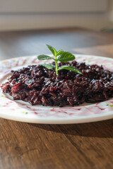 black rice dish on white plate in close-up