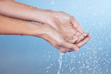 Hands, water and person washing for health, cosmetics and wellness cleaning or grooming. Fresh, palm rinsing and droplet in studio blue background for skin care, morning routine and hygiene or pamper