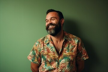 Obraz premium Portrait of a handsome bearded man smiling at the camera. Green background.