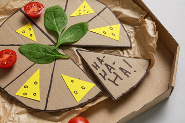 Carton pizza with tomatoes and basil on white background. April Fools Day prank