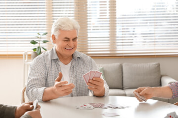 Old man playing cards at home