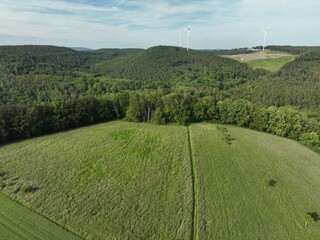 Windkraftanlagen mitten im Grün umgeben von Gebirgen in Rheinland-Pfalz