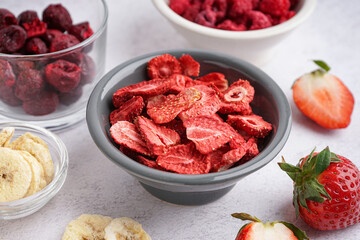 Bowl with sweet freeze-dried strawberries on white background