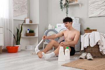 Young man taking off socks on floor in laundry room