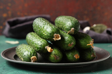 Plate with fresh cucumbers on green table