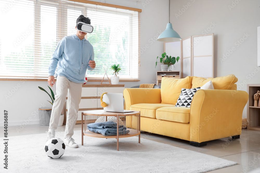 Poster teenage boy in vr glasses playing with soccer ball at home