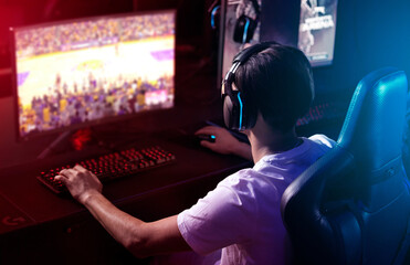 Gamer, computer screen and man with headphones, night and esports subscription from back. Content creator, influencer or streamer with headset for online challenge, video game or live stream at home. © FrameFlex/peopleimages.com