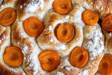 Close-up of a sweet apricot Ensaimada with powdered sugar, showcasing traditional Mallorca lard pastry perfect for use in culinary marketing, bakery advertisements and Mediterranean dessert promotions