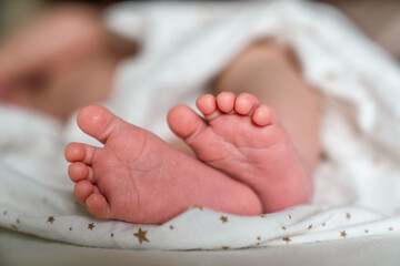 close up baby legs lying on bed at home