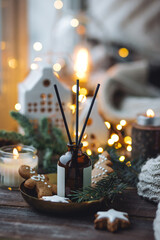 Aromatic home apartment diffuser with the fresh pine fragrance, gingerbread cookies scent. Fir tree branches, essential oils, candle, holiday decor. Cozy festive atmosphere, Christmas spirit