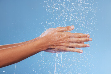 Fototapeta premium Person, hands and water for germs in studio, washing and grooming for skincare on blue background. Palms, cleaning and liquid for cosmetics or bacteria and virus protection, disinfect and hydration