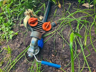 A close-up shot of a manual garden sprinkler valve on moist soil, symbolizing efficient watering practices in gardening.