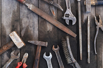 Old work tools on a plank wooden background, top view. Hammers, flat file, tin snips, brush, adjustable wrench and wrench. Hand tool. Builder's Day or Father's Day. Construction and renovation concept