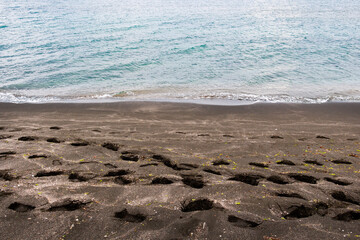 Footprints on the black sand of the spit between Lake Pomorie and the Black Sea at Pomorie, Province of Burgas, Bulgaria