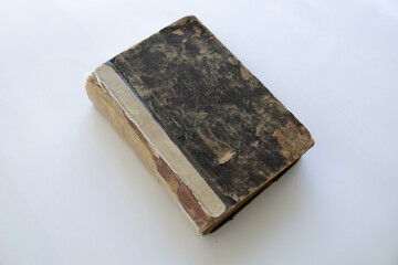damaged cover of a very old book in black colour. yellowed natural paper texture. isolated on white background. clean close-up.