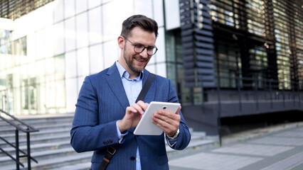 Fototapeta premium Young businessman using tablet in front of his company