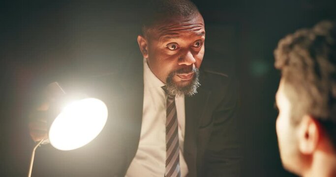 Detective, suspect and question in interrogation room for lamp light, investigation or arrest. Law enforcement, policeman and male criminal in conversation for legal justice, interview or crime