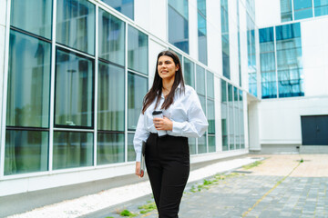 One young successful business woman going to work at business office modern building while holding coffee and papers	