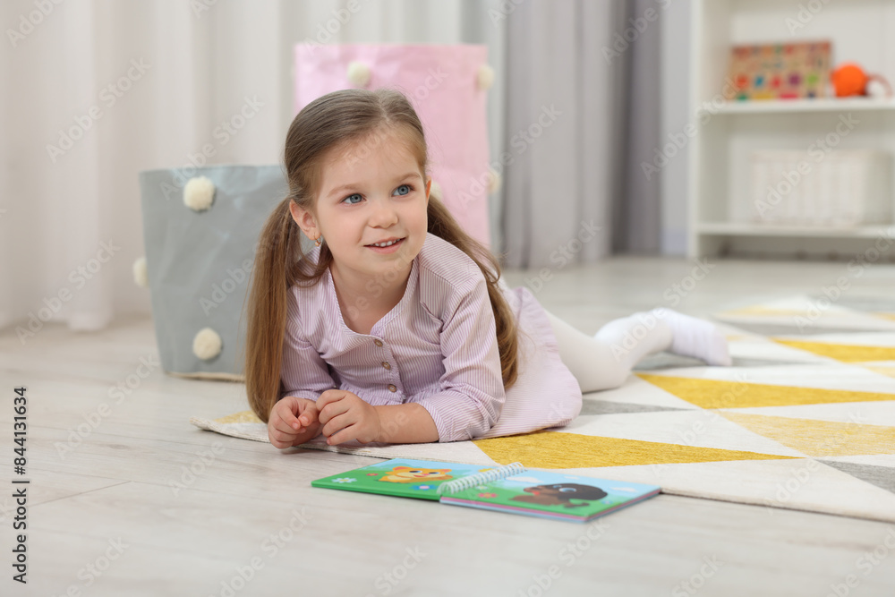 Sticker Cute little girl with book on floor in kindergarten