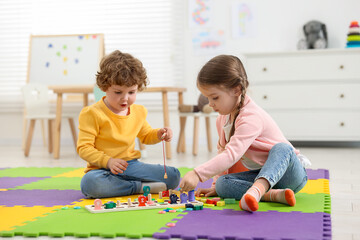 Cute little children playing with math game Fishing for Numbers on puzzle mat in kindergarten