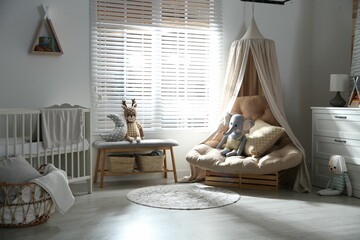 Beautiful baby room interior with comfortable armchair and bench near window