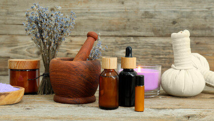 Different aromatherapy products, burning candle and lavender on wooden table