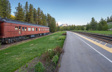Fototapeta premium Train tracks and historic passenger train car at the Lake Louise Train Station in Banff National Park, Alberta, Canada
