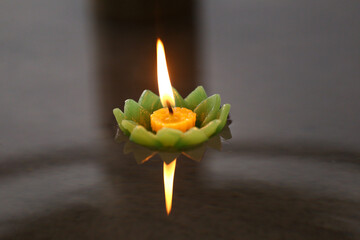 Candles of Krathong with flames floating on the water.