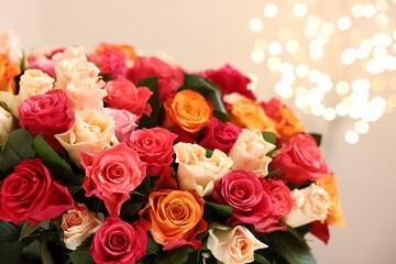 Beautiful bouquet of colorful roses on beige background, closeup