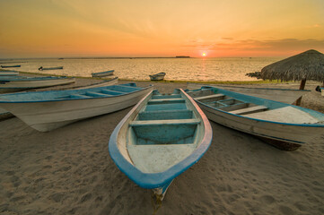 Summer vacations and adventure in La Paz Baja California Sur. Mexico. Pangas or boats on the beach at the malecon with sunset and el mogote in the background.