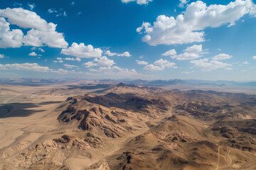 Obraz premium Aerial view of a desert landscape photographed by a drone, presenting an expansive vista of sand and mountains, ideal for wallpapers that reflect the serene of a dessert