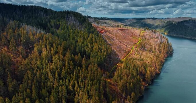 Pine tree forest covering the mount partially. Touristic trails cross the rock. River flows at the foot of the mountain. Dramatic cloudscape is in the sky. Top view.