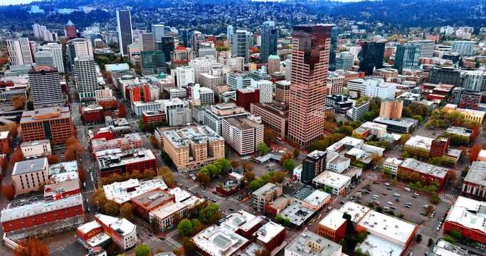 Varied urban landscape of Portland, Oregon, the USA. Drone footage over the city at day. Populated area on the mountains at backdrop.