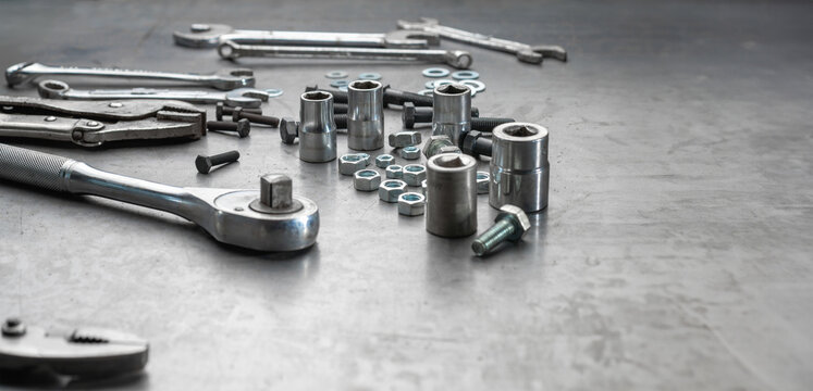 Open end wrench , socket wrench and nuts on steel work bench