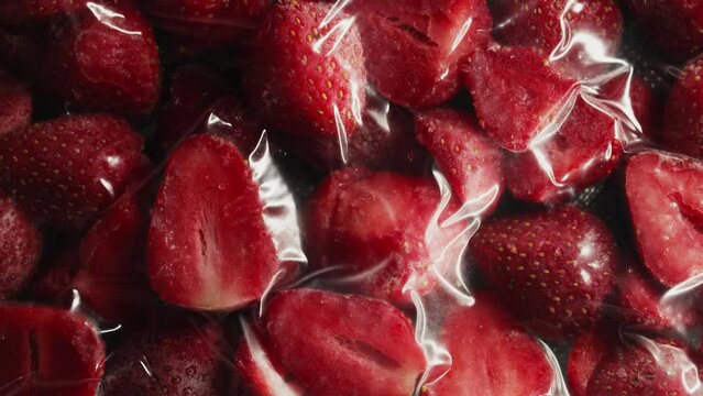 Vacuum packer extracts air from bag with frozen strawberry slices. Freezer storage preparation