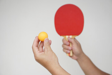 Selective focus on the orange ball on hand with serving table tennis racket. Concept, sport equipment. Exercise or workout tool. Competitive game sport. Playing Ping pong    