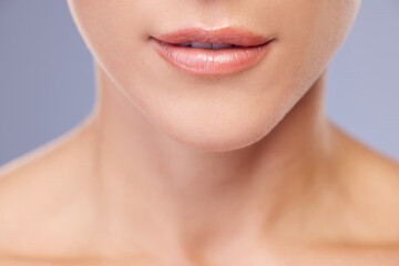 Obraz premium Woman, lips and skincare in studio for beauty, facial treatment and cosmetics on blue background. Female person, mouth and pamper for dermatology, grooming and confident for soft skin or wellness