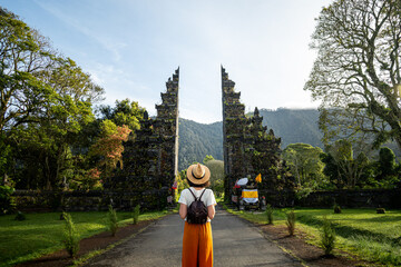 Woman tourist with backpack enjoying walk through Balinese Hindu temple during vacation. Woman...