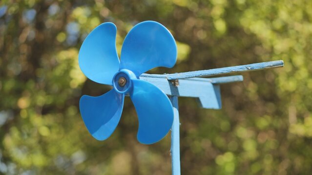 A blue vane weathervane spins in the wind in the summer.